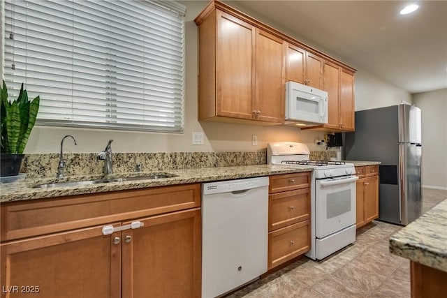 kitchen with light stone countertops, sink, and white appliances