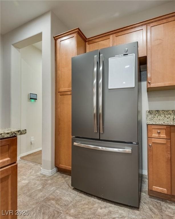 kitchen with stainless steel fridge and light stone countertops