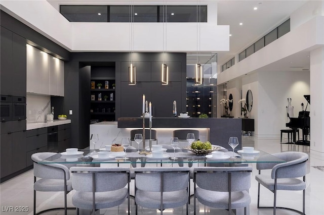 bar featuring a high ceiling, black oven, and decorative light fixtures