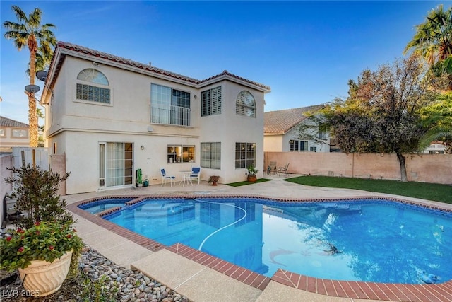 rear view of house with a fenced backyard, a patio, a tiled roof, and stucco siding