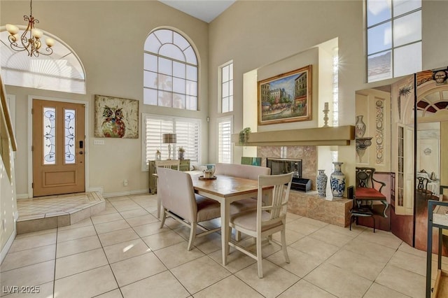 tiled dining space with a fireplace, a high ceiling, and a chandelier