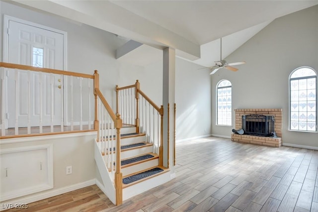 interior space with a brick fireplace, high vaulted ceiling, and ceiling fan