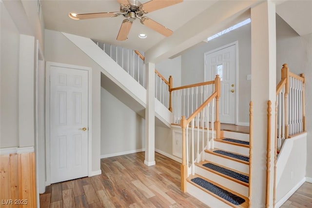 staircase with ceiling fan and hardwood / wood-style flooring