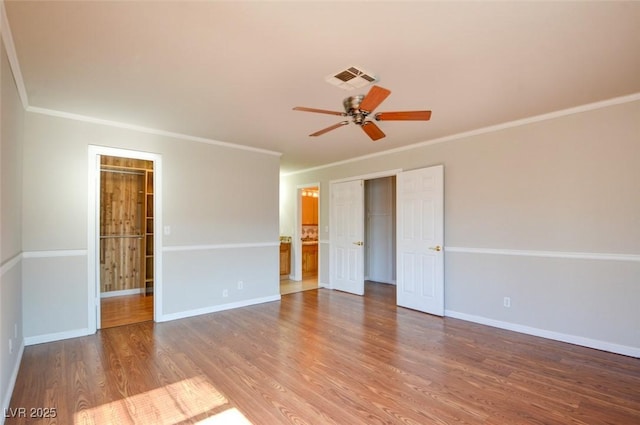 empty room featuring hardwood / wood-style flooring, ornamental molding, and ceiling fan