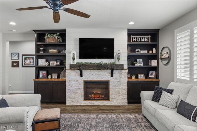 living room with ceiling fan, a stone fireplace, and dark hardwood / wood-style flooring