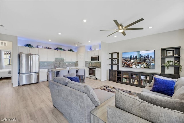 living room with sink, ceiling fan, and light hardwood / wood-style floors