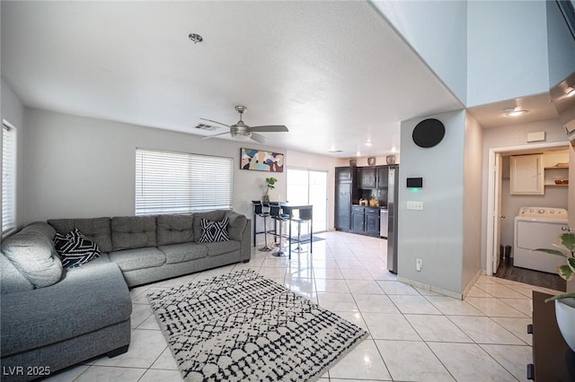 tiled living room featuring ceiling fan and washer / clothes dryer