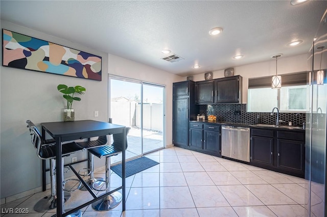 kitchen with pendant lighting, stainless steel dishwasher, tasteful backsplash, sink, and light tile patterned floors