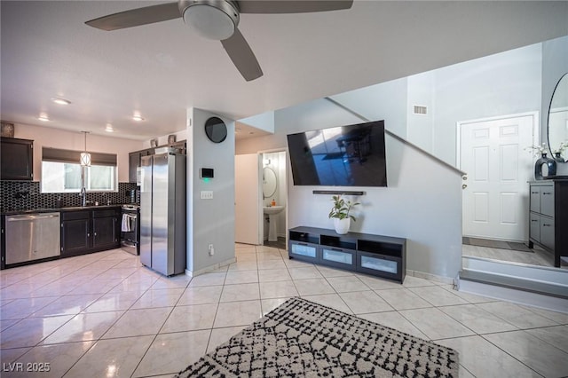 kitchen featuring ceiling fan, sink, backsplash, light tile patterned flooring, and stainless steel appliances