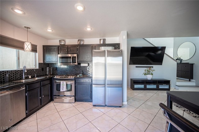 kitchen with light tile patterned floors, sink, dark brown cabinetry, decorative light fixtures, and stainless steel appliances