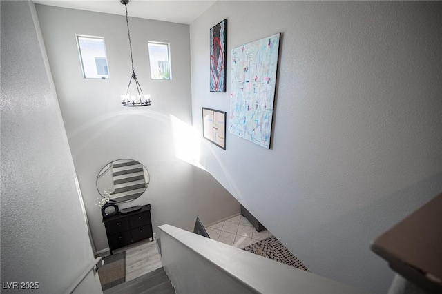 staircase with wood-type flooring and a notable chandelier