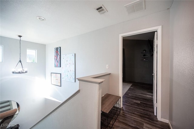 hall with dark hardwood / wood-style floors and a notable chandelier