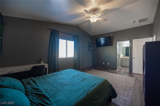 bedroom featuring lofted ceiling, black refrigerator, dark hardwood / wood-style floors, ceiling fan, and ensuite bathroom