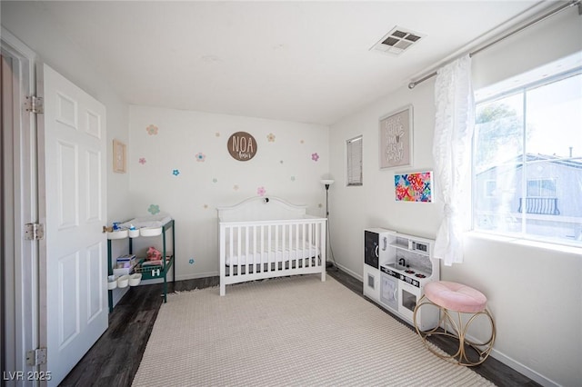 bedroom featuring a crib and dark hardwood / wood-style floors