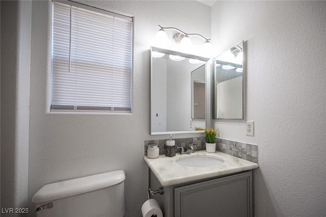 bathroom with vanity, toilet, and tasteful backsplash