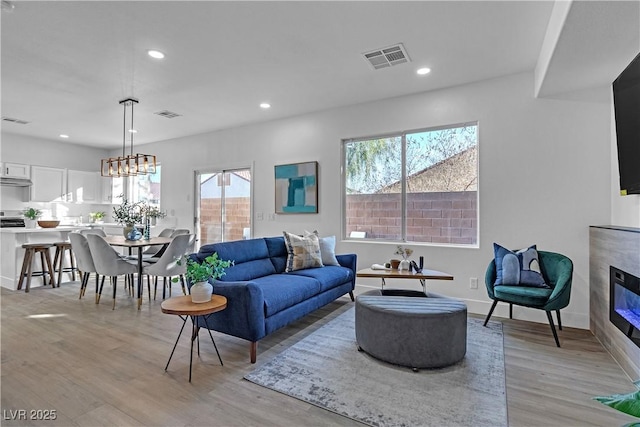 living room with light wood-type flooring and an inviting chandelier