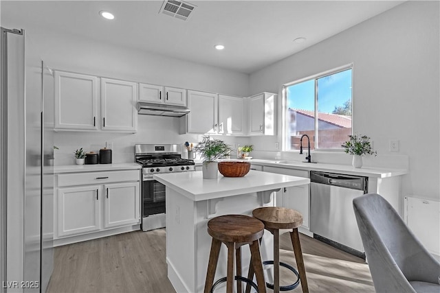 kitchen with sink, white cabinets, light hardwood / wood-style floors, and stainless steel appliances