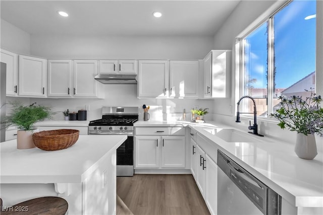 kitchen with wood-type flooring, sink, white cabinetry, a breakfast bar, and stainless steel appliances