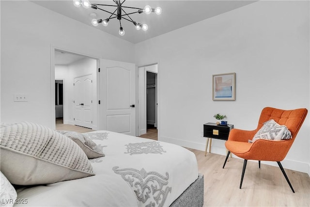 bedroom with a chandelier, a closet, light hardwood / wood-style flooring, and a walk in closet