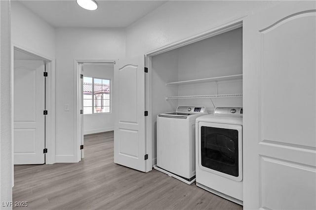 clothes washing area featuring independent washer and dryer and light hardwood / wood-style flooring