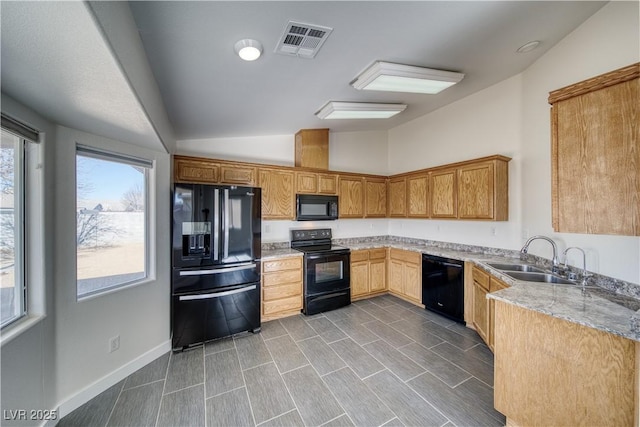 kitchen with black appliances, light stone countertops, lofted ceiling, and sink