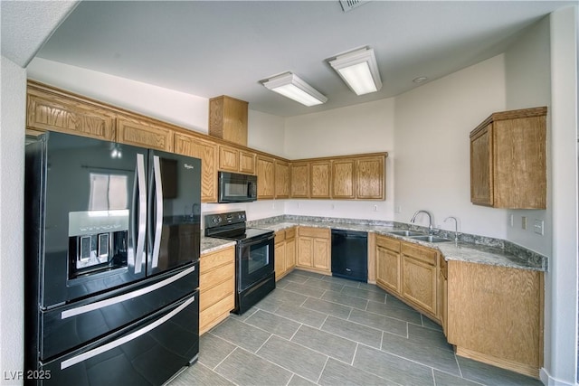 kitchen featuring black appliances, light stone counters, and sink