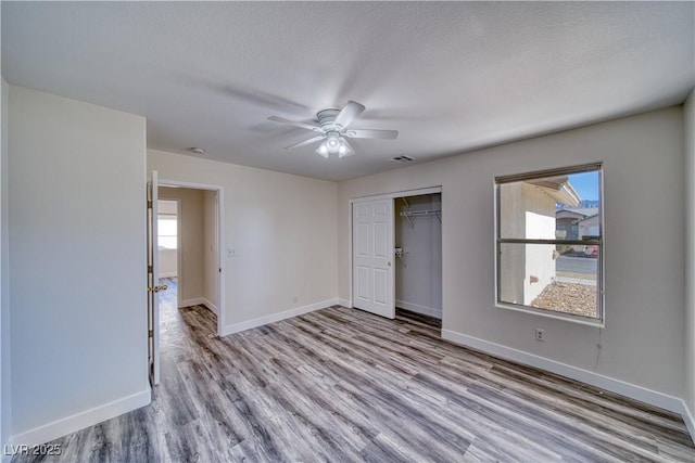 unfurnished bedroom featuring a closet, ceiling fan, light hardwood / wood-style floors, and multiple windows