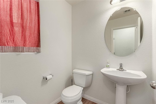 bathroom with hardwood / wood-style flooring and toilet