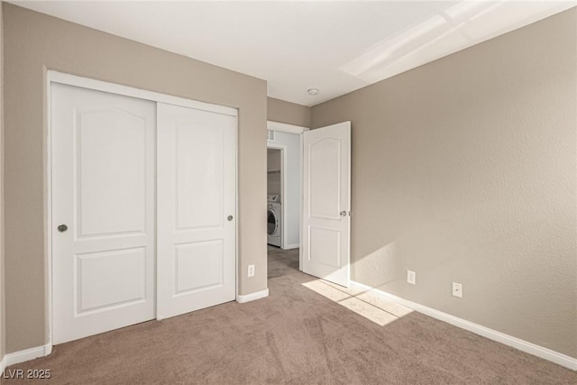 unfurnished bedroom with washer / dryer, light colored carpet, and a closet