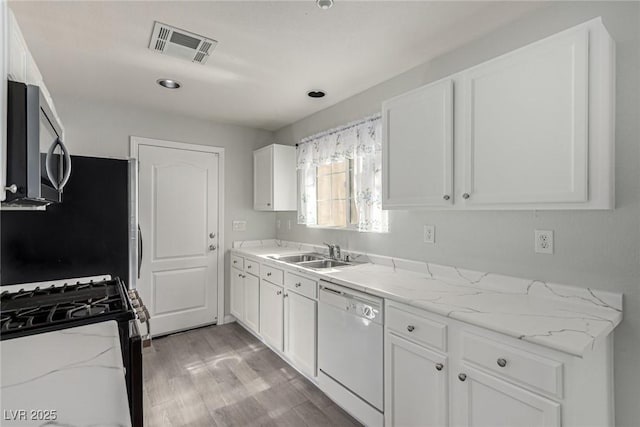 kitchen featuring white cabinetry, dishwasher, sink, light stone counters, and gas range oven