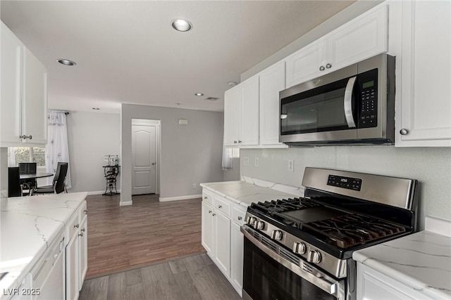 kitchen featuring light stone counters, wood-type flooring, white cabinets, and appliances with stainless steel finishes