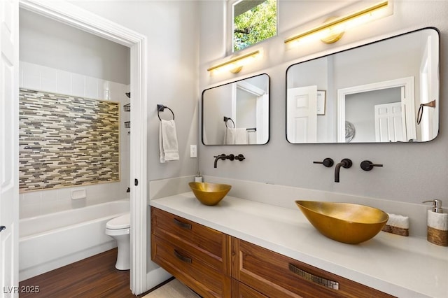 full bathroom featuring toilet, wood-type flooring, vanity, backsplash, and tub / shower combination