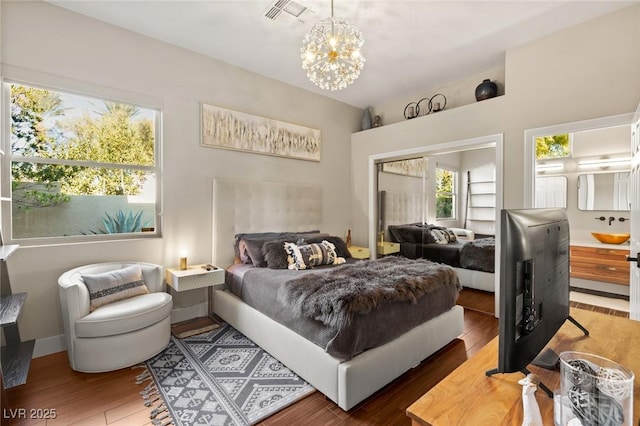 bedroom featuring multiple windows, hardwood / wood-style flooring, and an inviting chandelier