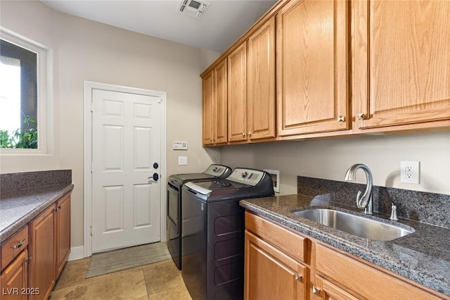 clothes washing area featuring sink, cabinets, and washer and dryer