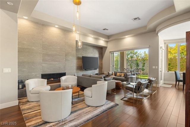 living room with tile walls, a tile fireplace, and dark hardwood / wood-style flooring