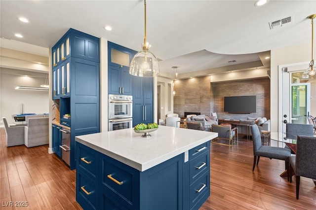 kitchen with a kitchen island, blue cabinetry, and hanging light fixtures