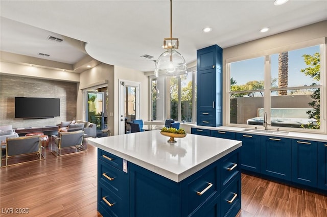 kitchen with a center island, decorative light fixtures, dark hardwood / wood-style flooring, sink, and blue cabinets