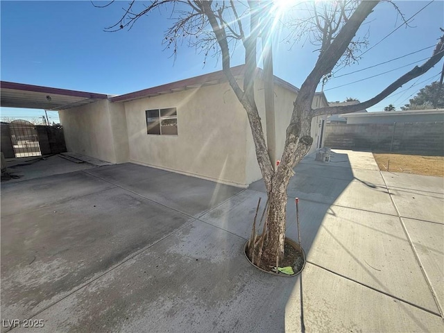 view of home's exterior with a patio area, a gate, fence, and stucco siding