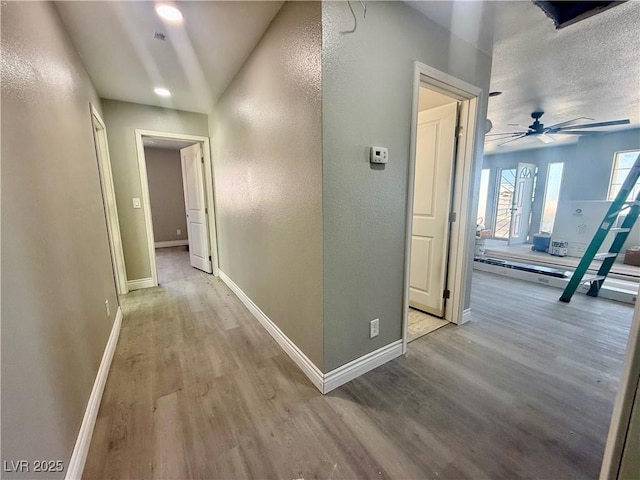 corridor featuring light wood finished floors and baseboards