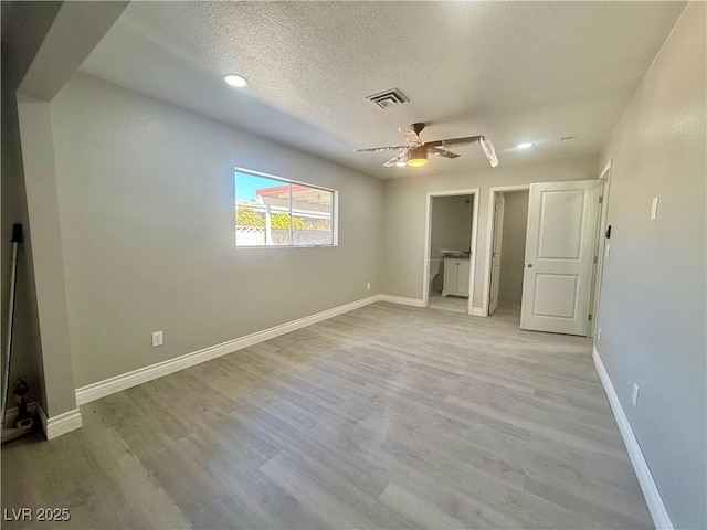 unfurnished bedroom featuring light wood finished floors, visible vents, baseboards, and a textured ceiling