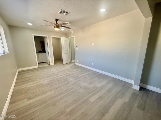 unfurnished bedroom with a textured ceiling, light wood finished floors, visible vents, and baseboards