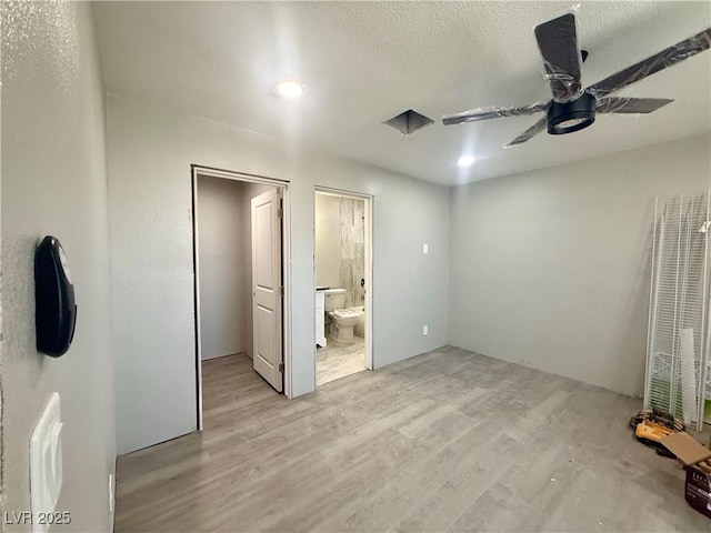 unfurnished bedroom featuring light wood-type flooring, ceiling fan, a textured ceiling, and ensuite bath