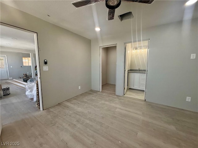 unfurnished bedroom featuring light wood-type flooring, a textured ceiling, and ensuite bathroom