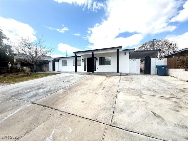 single story home featuring stucco siding, a gate, fence, concrete driveway, and an attached carport