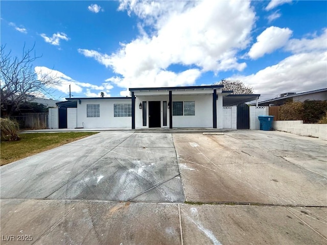 ranch-style house featuring stucco siding, an attached carport, driveway, and fence