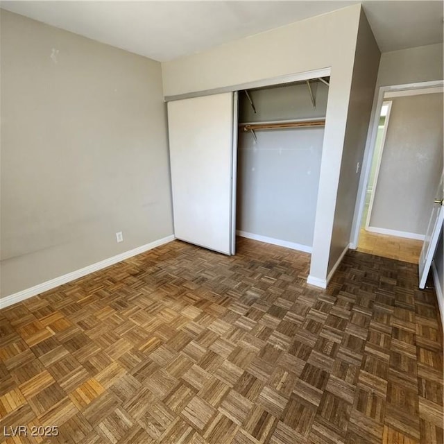 unfurnished bedroom featuring a closet and dark parquet flooring