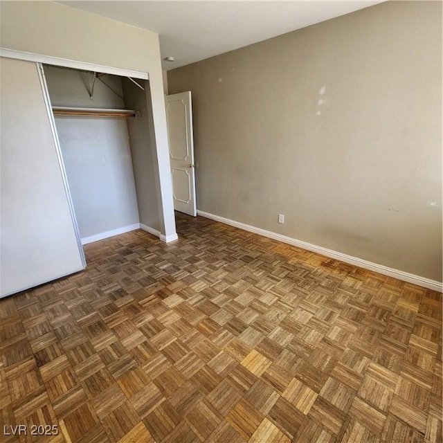 unfurnished bedroom featuring parquet flooring and a closet