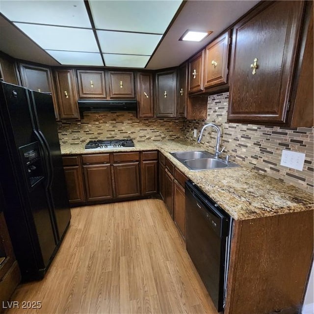 kitchen with dark brown cabinetry, black appliances, decorative backsplash, sink, and light wood-type flooring