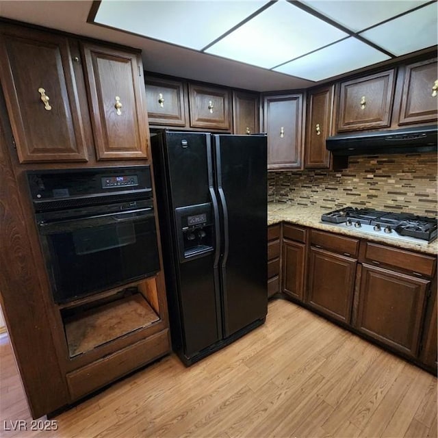 kitchen featuring dark brown cabinets, black fridge, and stainless steel gas cooktop