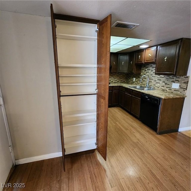 kitchen featuring dark brown cabinetry, dishwasher, decorative backsplash, sink, and light wood-type flooring